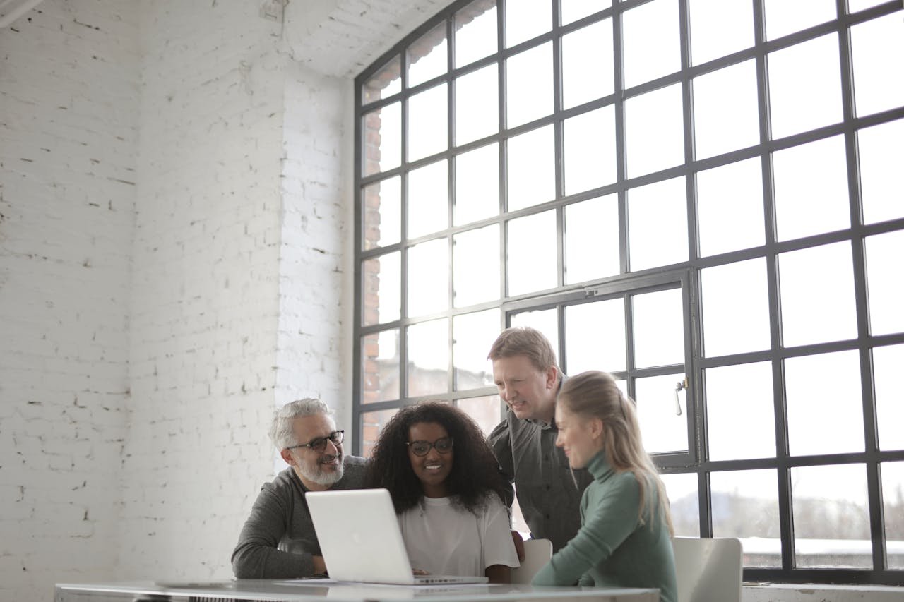 About Group of colleagues collaborating around a laptop in a bright, modern office space.